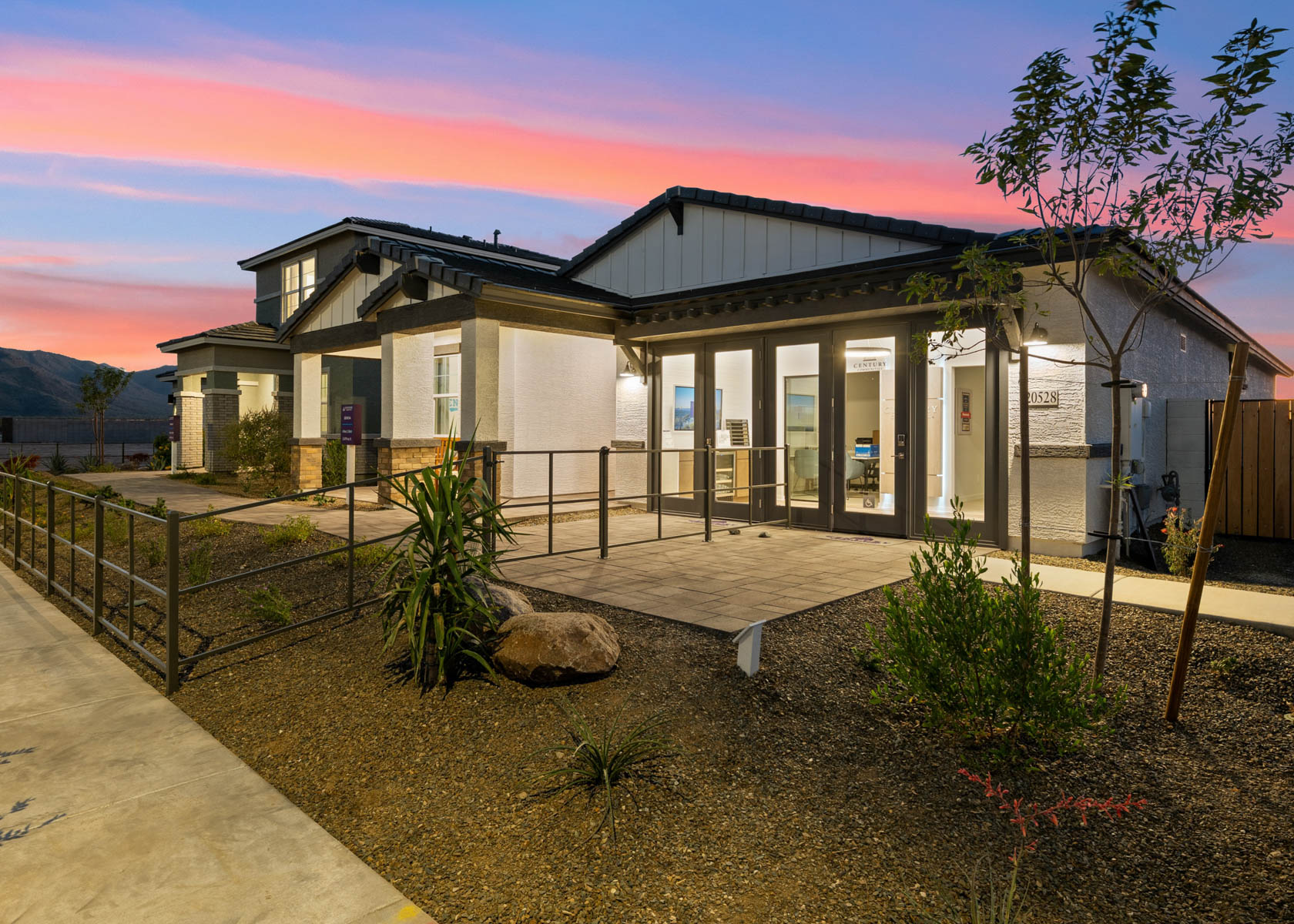 A building with a fence and a rock in front of it.