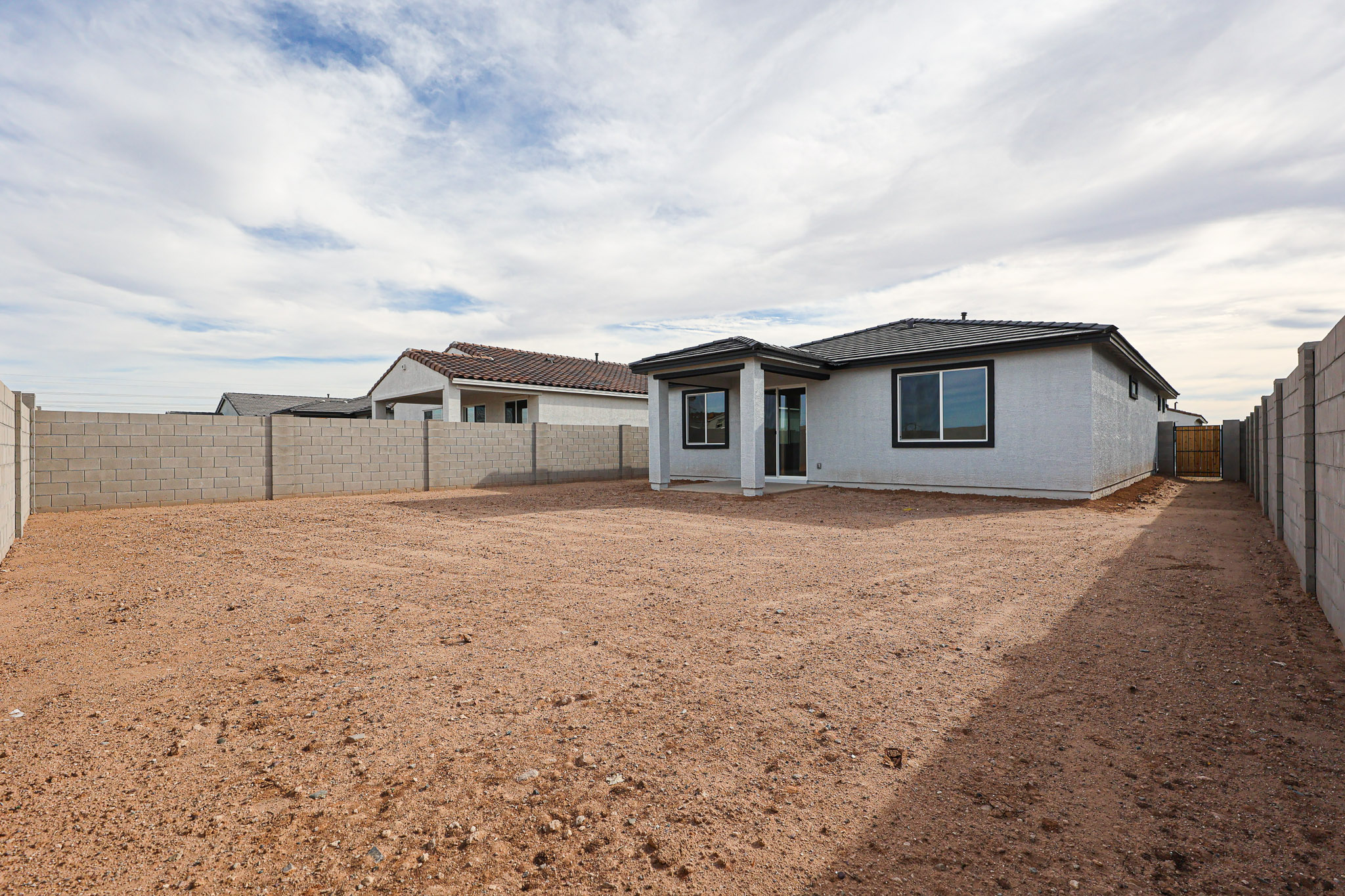 A dirt yard with a house in the background.