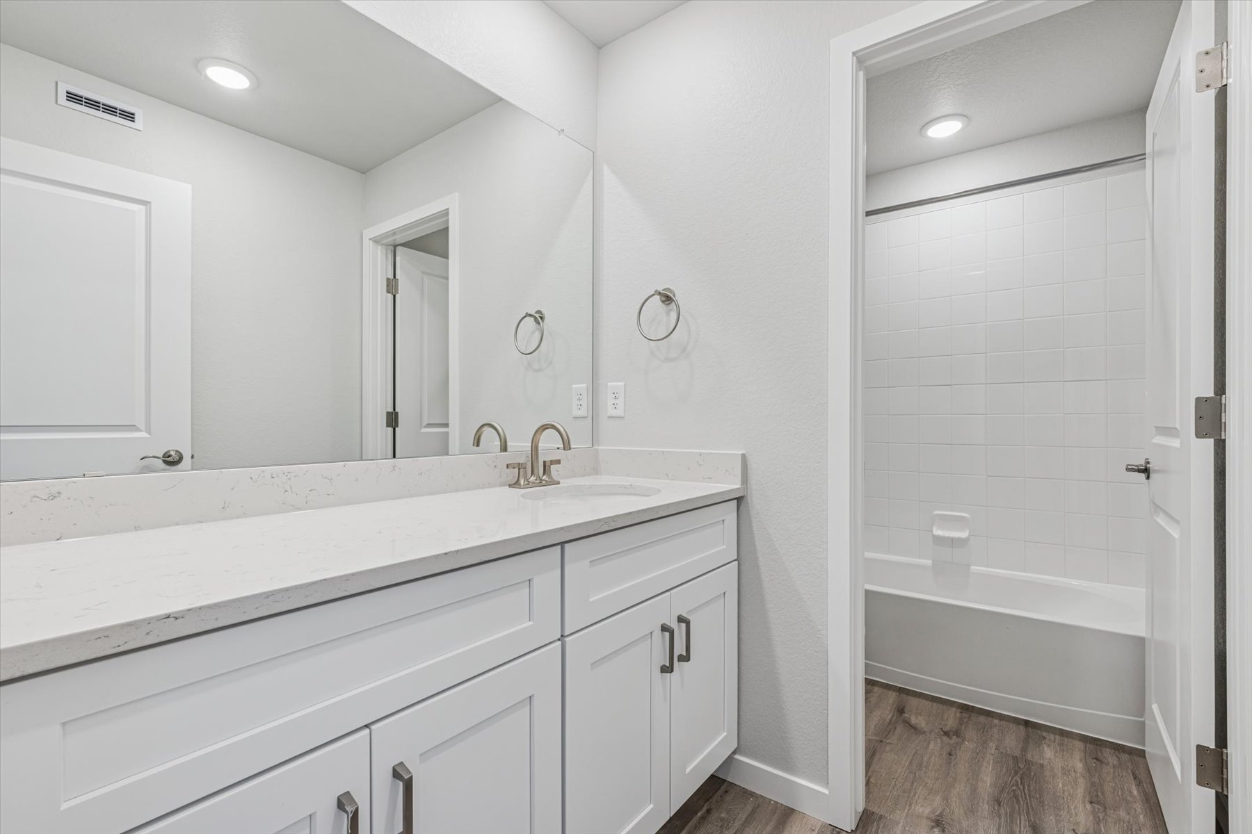 A bathroom with a tub sink and a mirror.