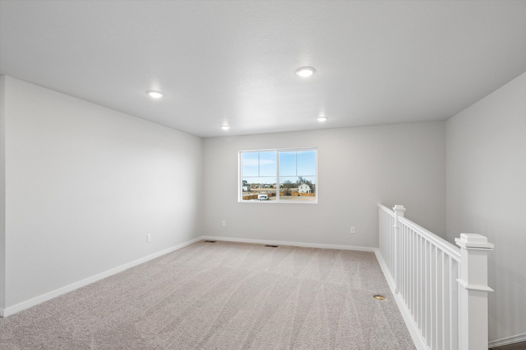 A room with a white railing and a window with a painting on it.