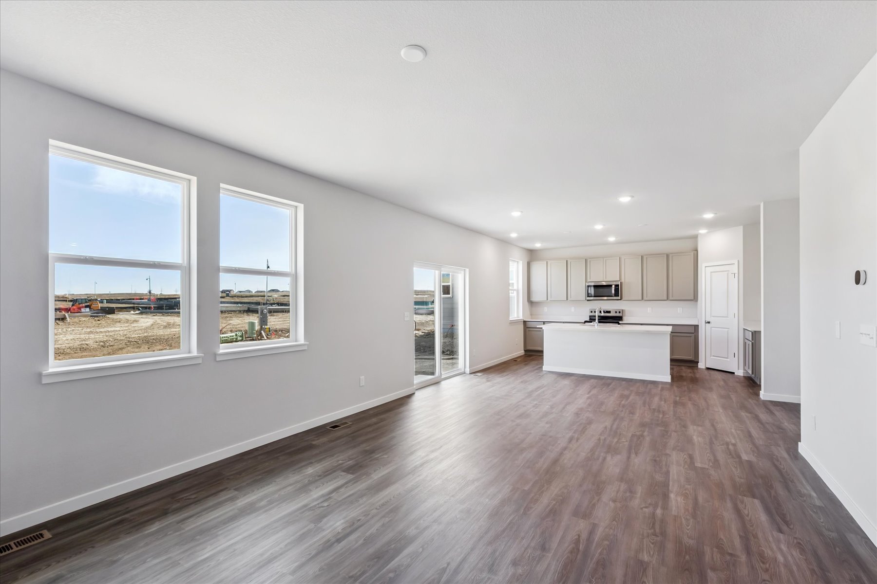 A large white room with a wood floor and a large window.