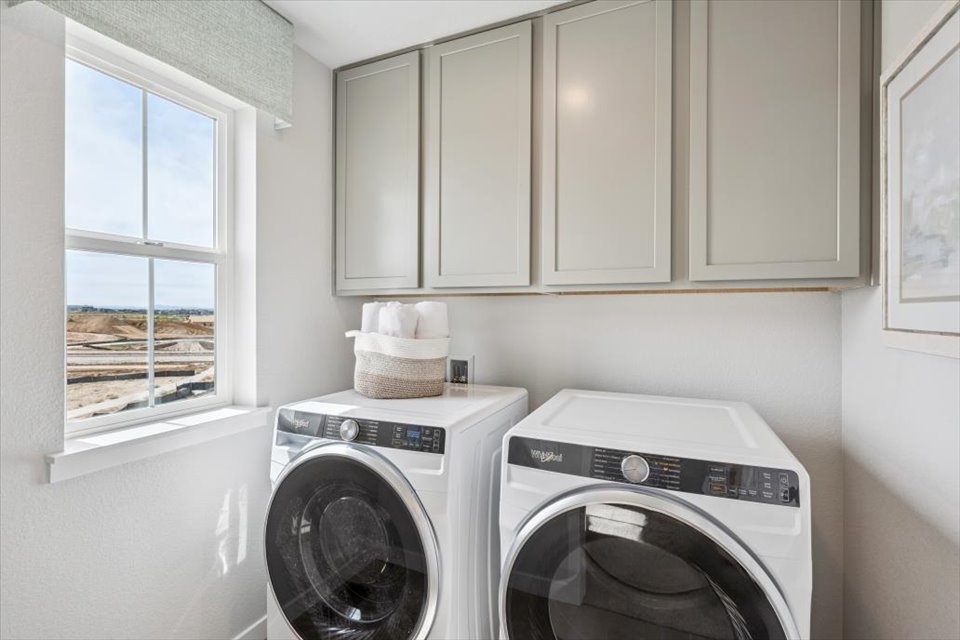 A laundry room with white cabinets.