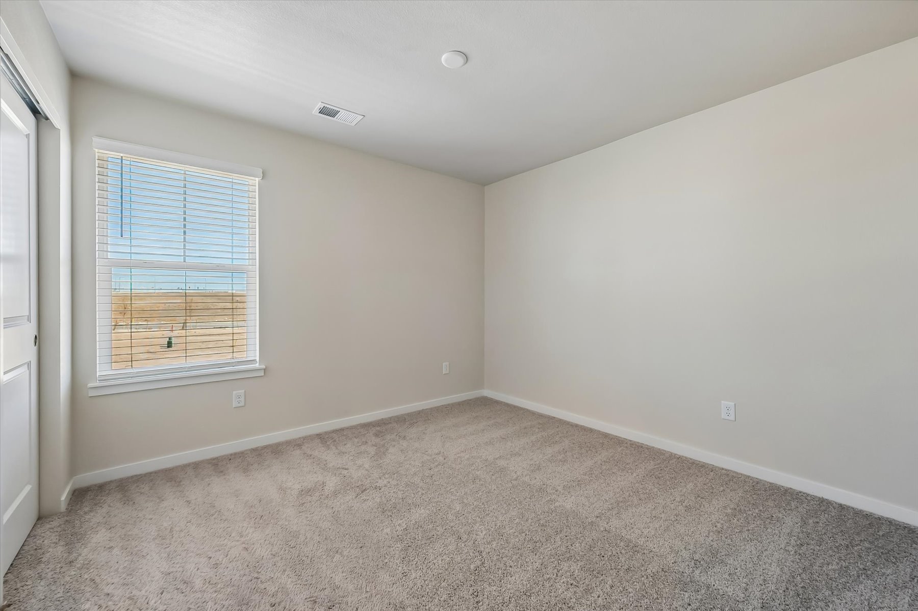 A room with a carpet and a window.