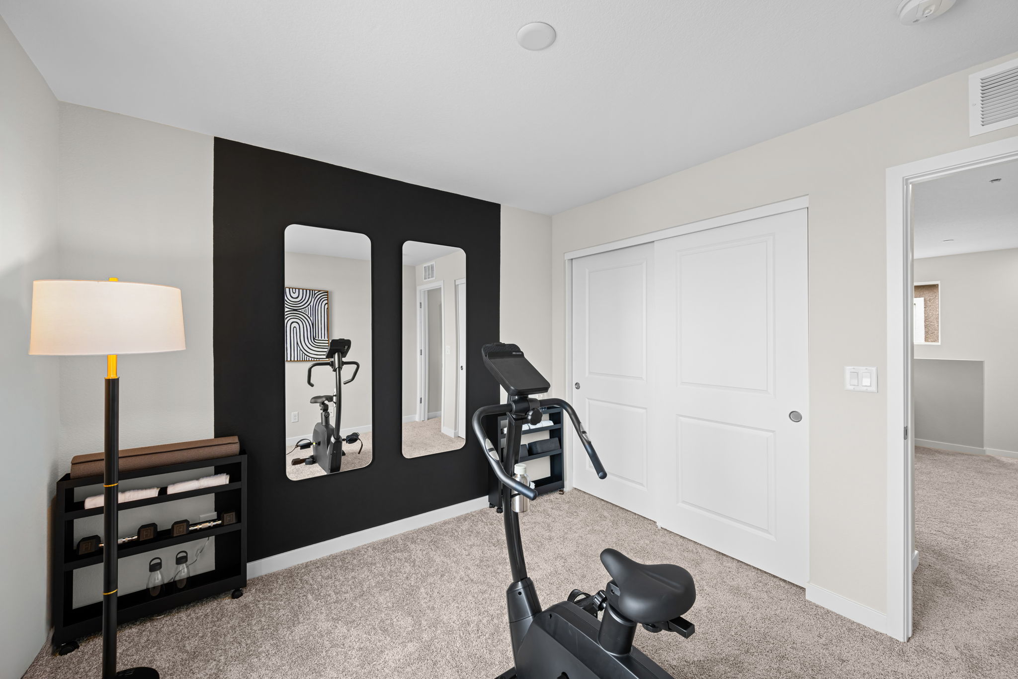 A room with a black chair and a lamp.