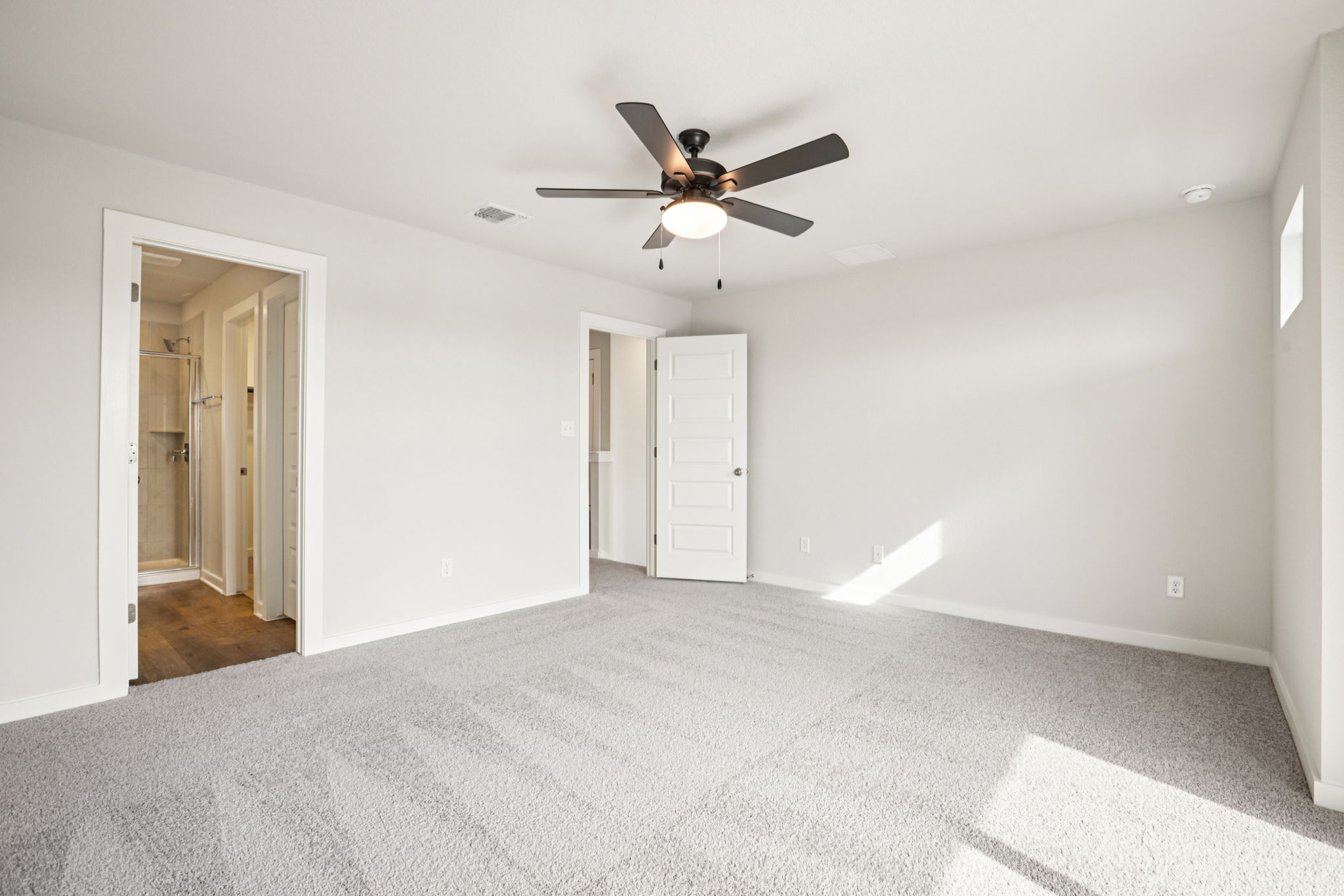 A room with a ceiling fan and a door.
