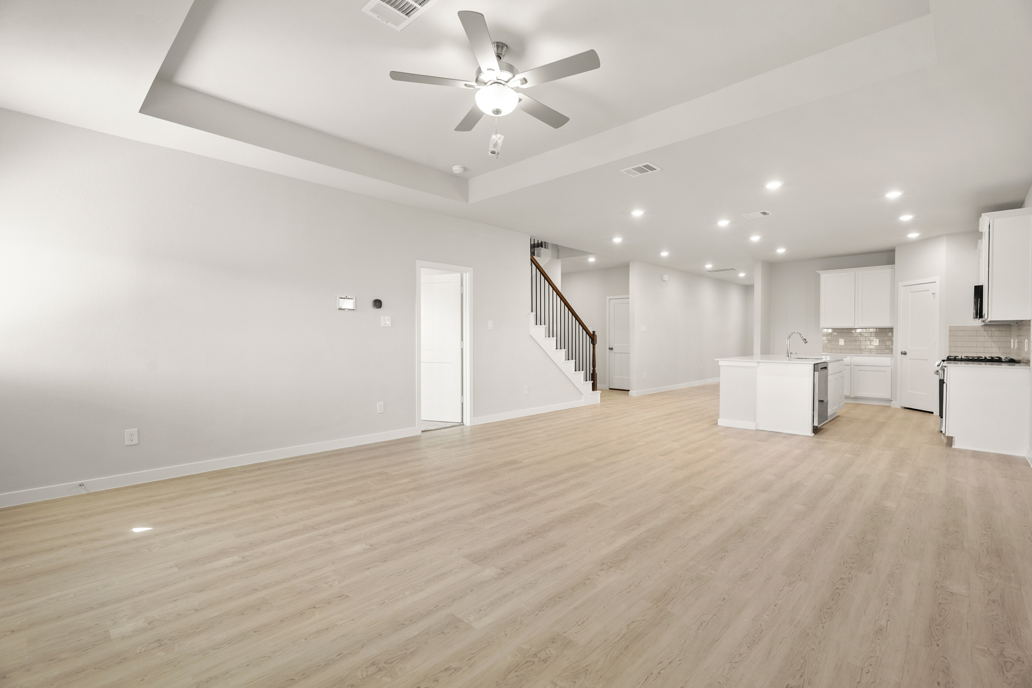 A large empty room with a wood floor and a ceiling fan.