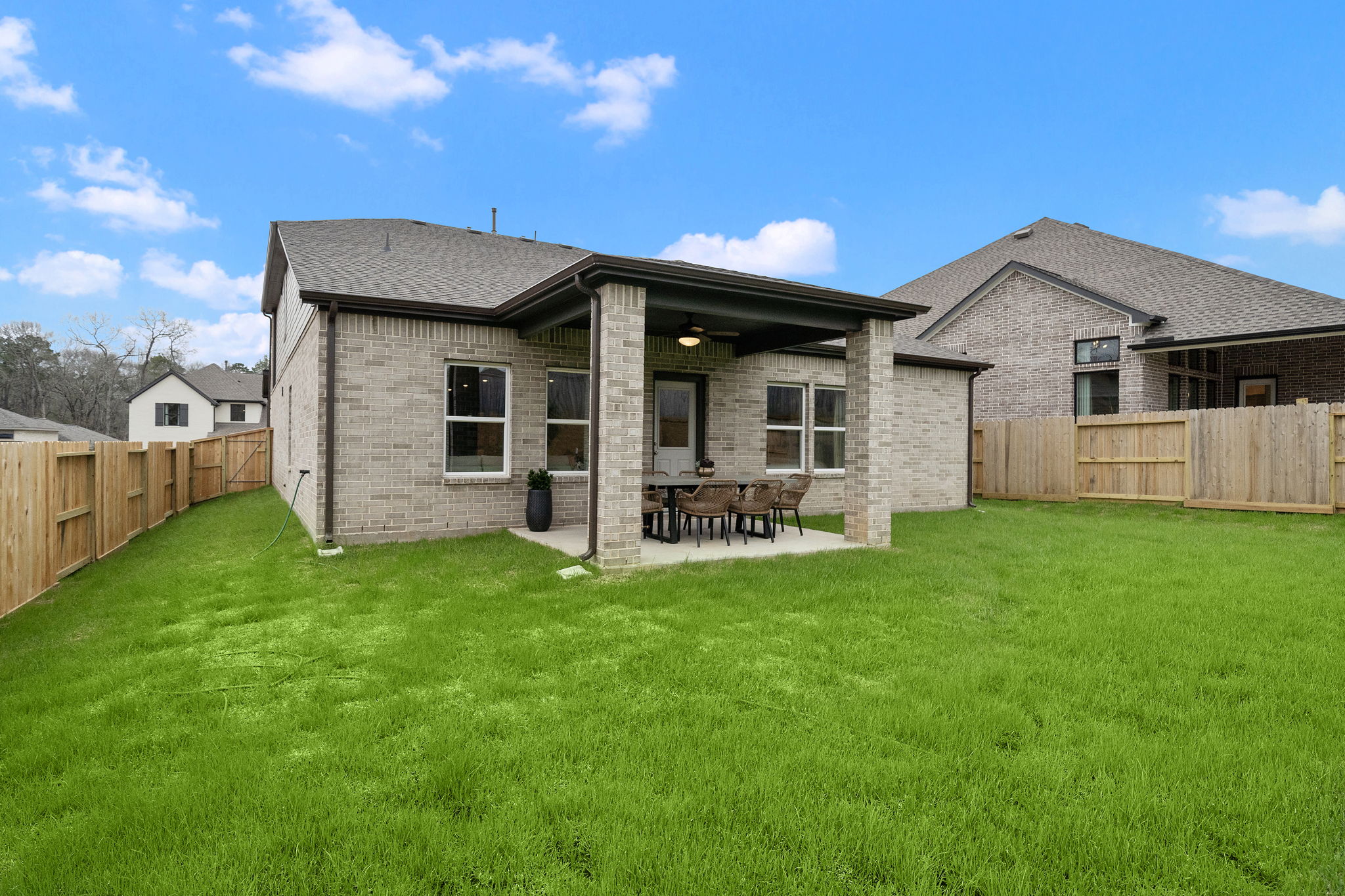 A house with a fence and a lawn in front of it.