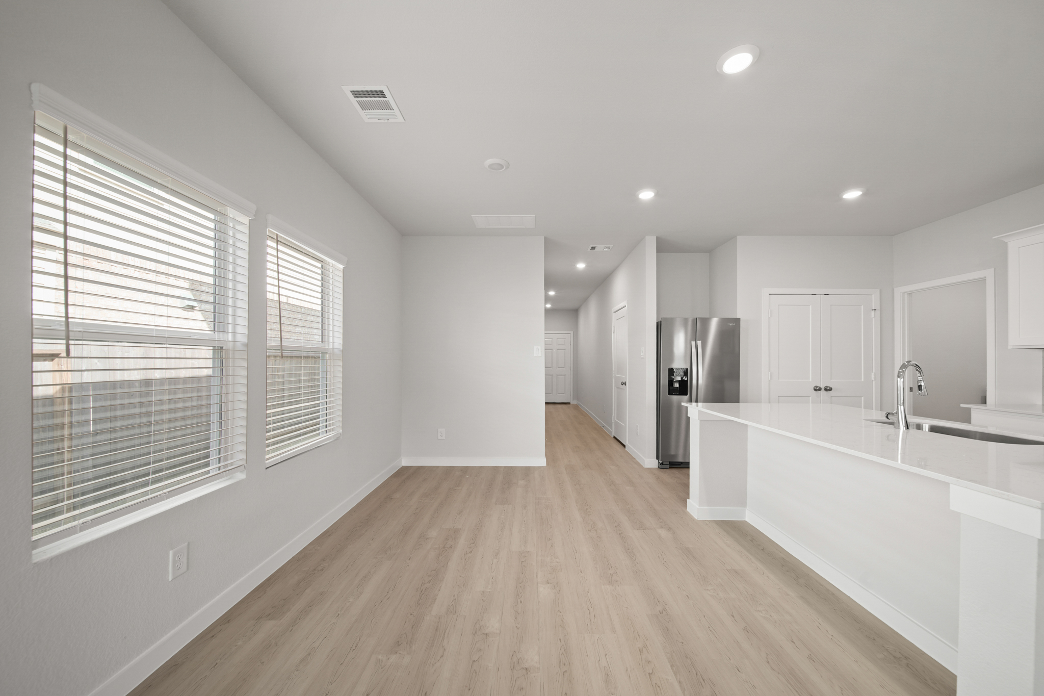 A large white kitchen with a wood floor.