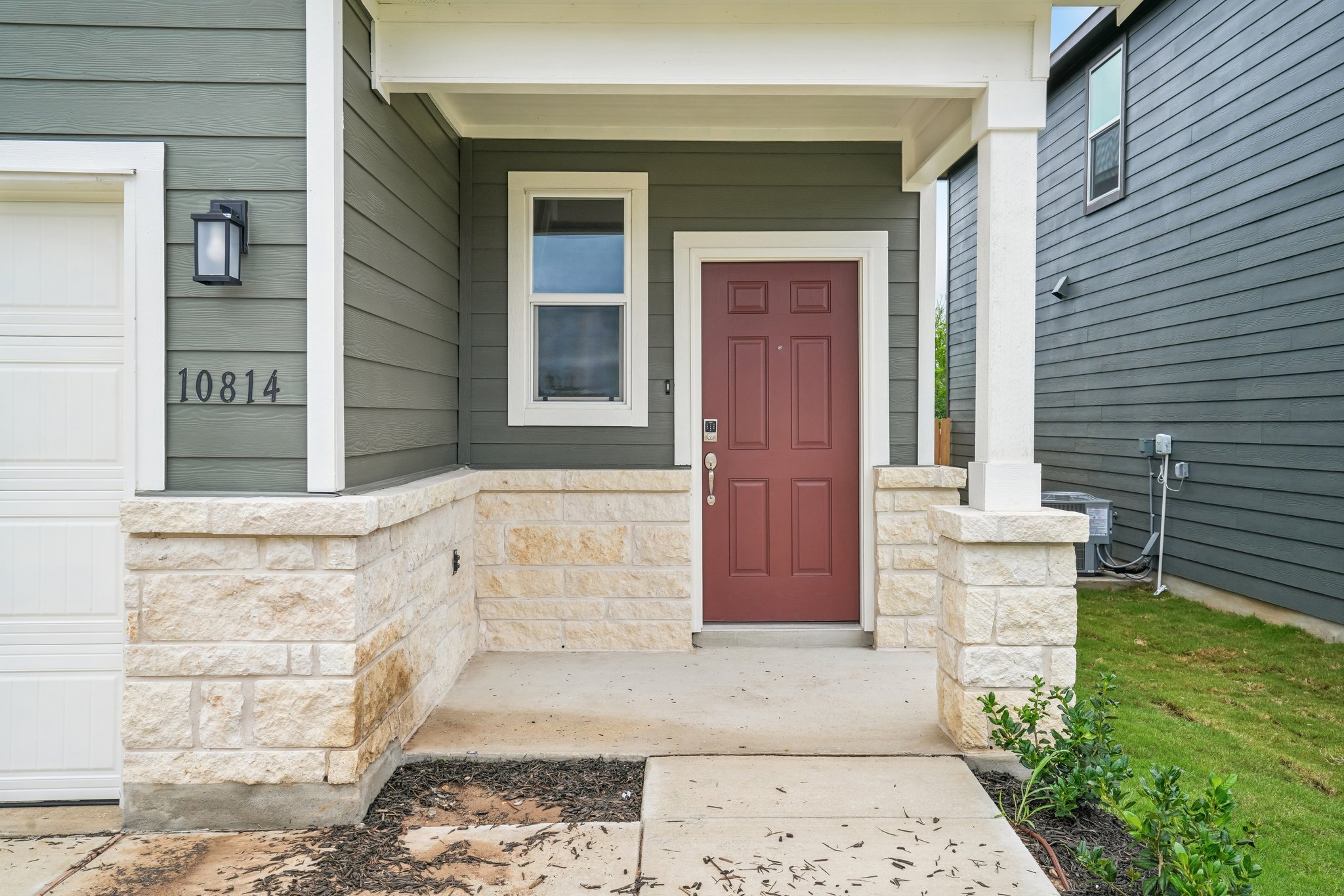 A house with a brick patio and a brick wall with a red door.