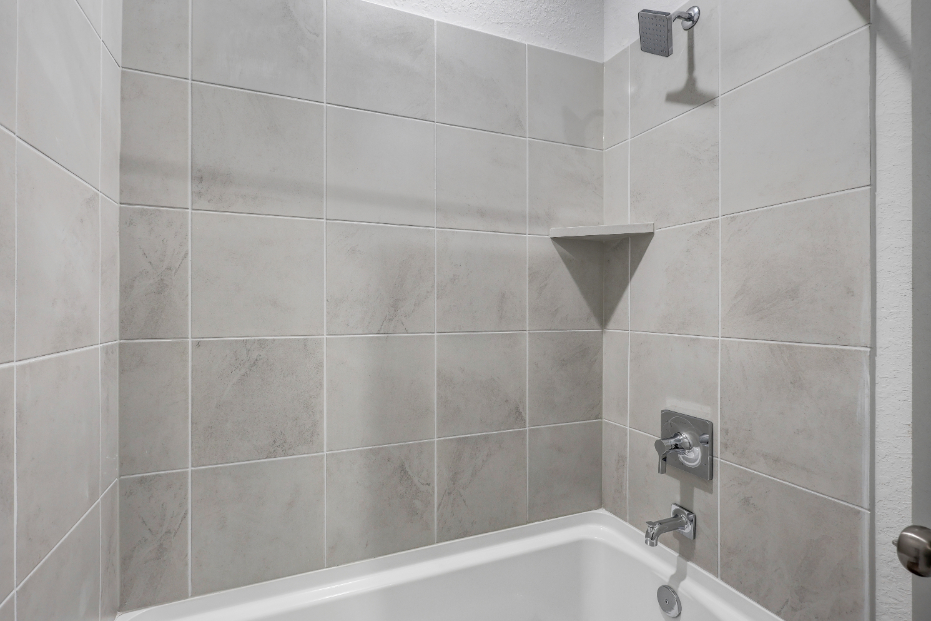 A bathtub with a tile wall.
