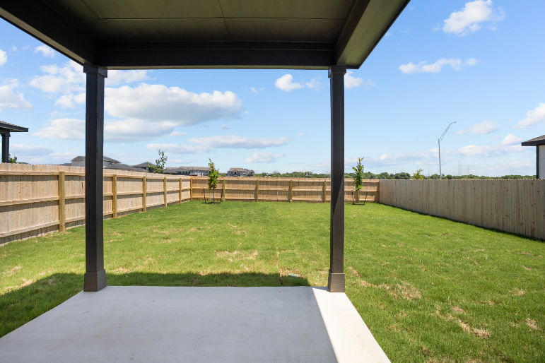 A backyard with a fence and a grass yard.