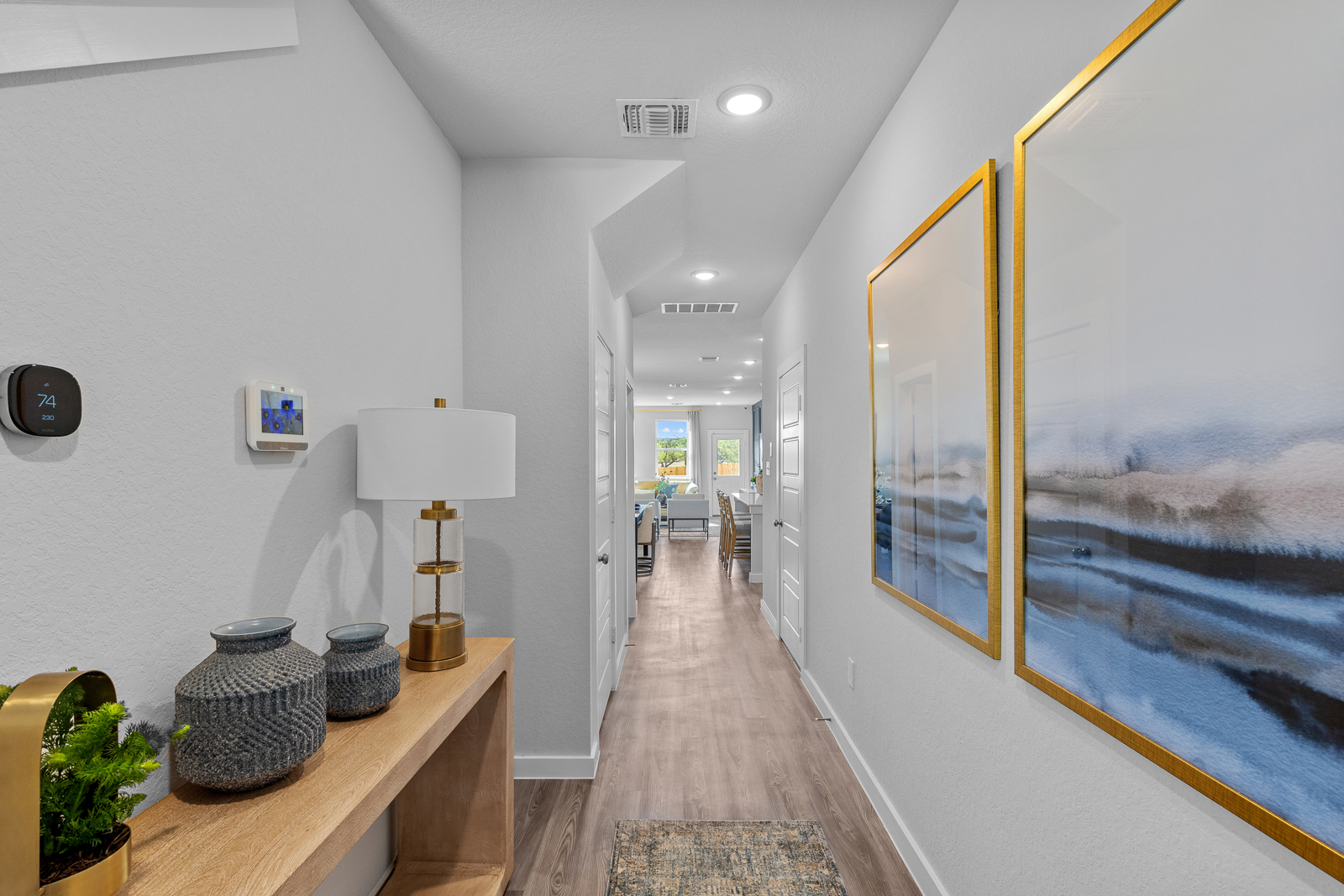 A hallway with a lamp and a painting on the wall.
