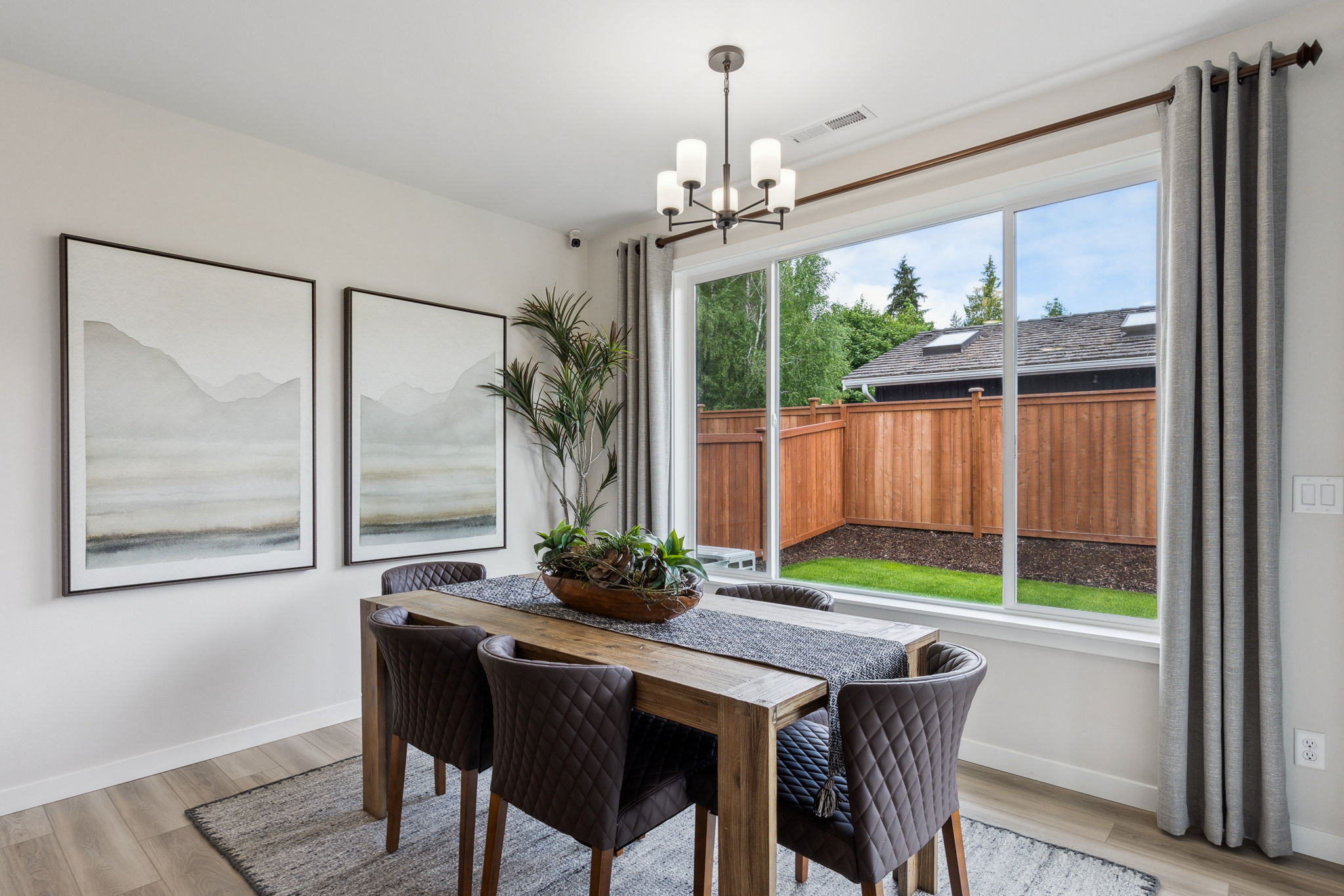 A dining room table with chairs and a window with a view of the ocean.