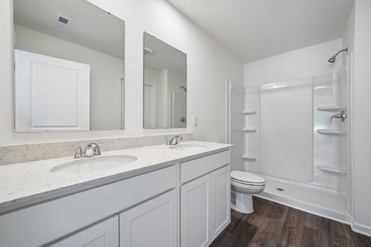A bathroom with a sink toilet and mirror.