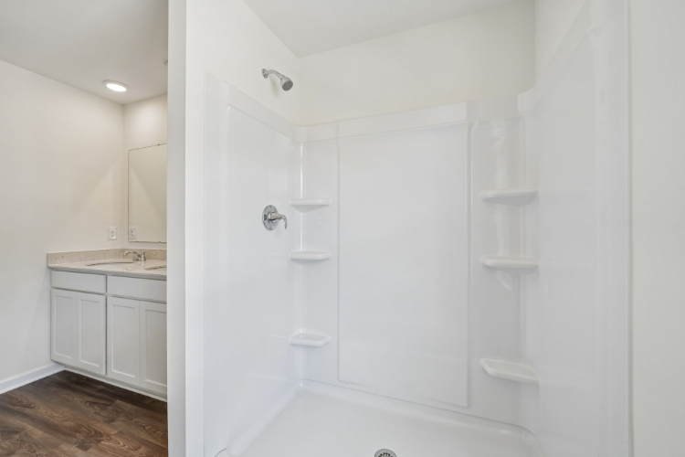 A bathroom with a shower unit and a sink.